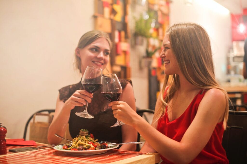 pexels photo 821054 two women holding long stem wine glasses with red liquid